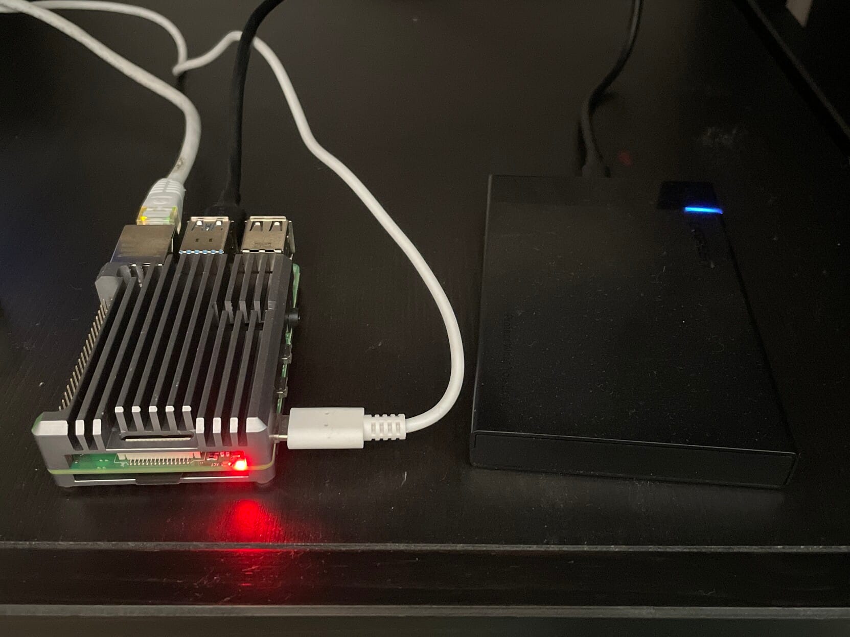 Una Raspberry Pi con una caja disipadora. A su lado hay un disco duro conectado por USB.